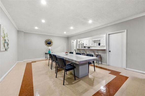 Recreation room with a large table and chairs, and a counter with stools, in a clubhouse setting.