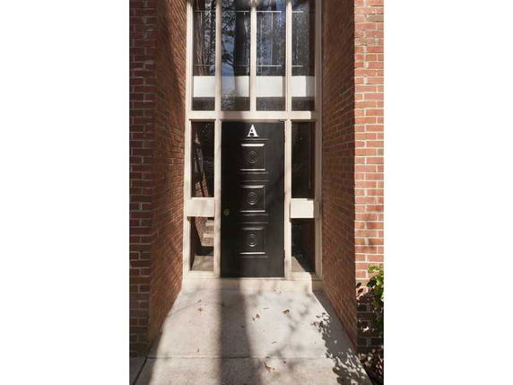 Front view of a building entrance with a black door and brick walls.