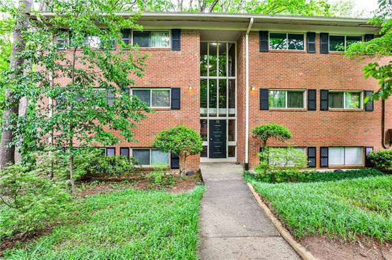 Front view of a three-story brick apartment building with multiple windows and a central entrance.