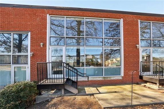 Front view of a red brick building with large glass windows and metal railings around steps.