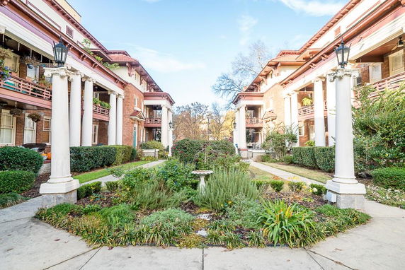 Front view of a multi-story building with columns and landscaped garden.
