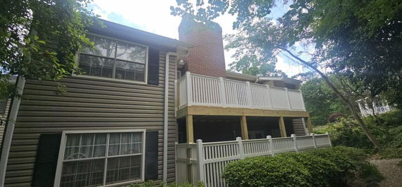 Front view of a two-story house with a brick chimney and a balcony with white railing.