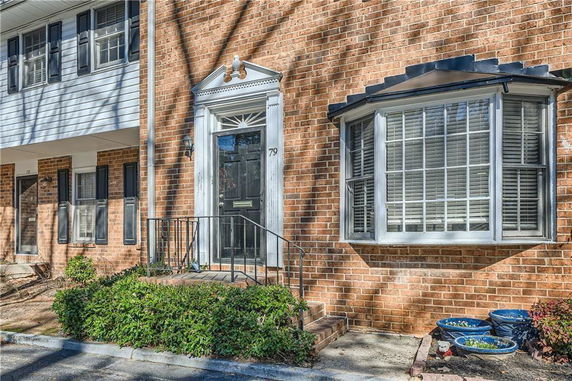 Front view of a brick townhouse with black door and bay window.