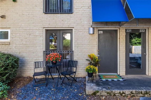 Front view of a building entrance with a door labeled 211 and a small outdoor seating area with a table and chairs.