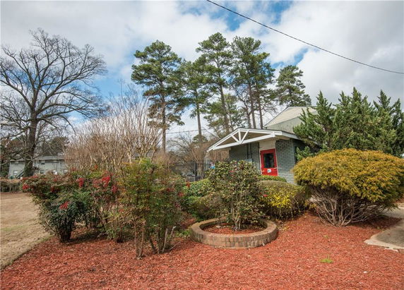 Front view of a small house with a red door and a gable roof.