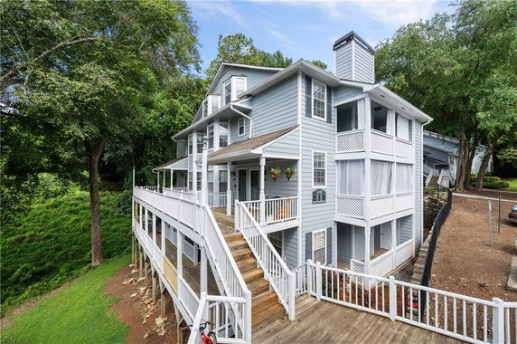 Front view of a multi-story house with wrap-around porch and large windows.