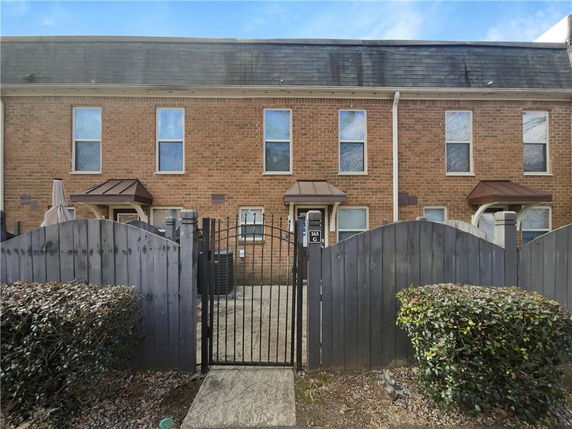 Front view of a two-story townhouse with brick exterior and gated entrance.