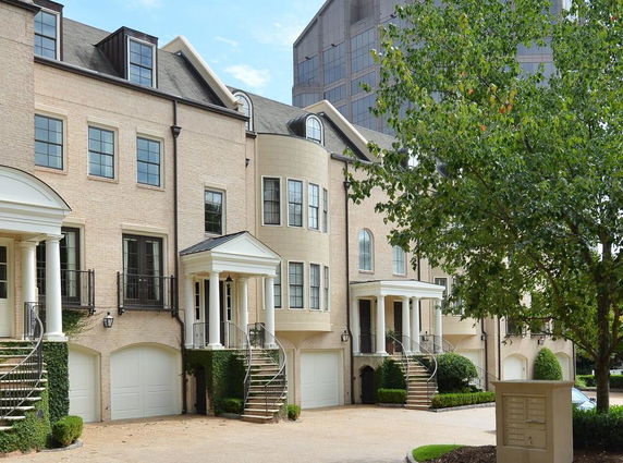 Front view of multi-story townhouses with garages and small porches.