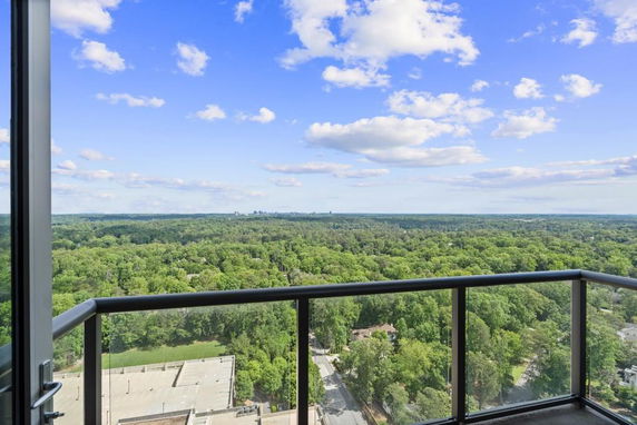 Panoramic view from a high-rise balcony overlooking a green landscape.