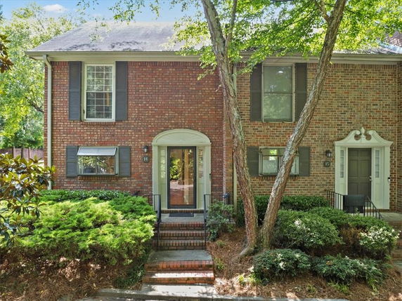 Front view of a two-story brick townhouse with shuttered windows and a central entrance.