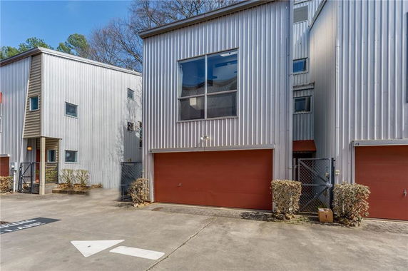 Front view of a modern multi-story building with metal siding and a double garage.