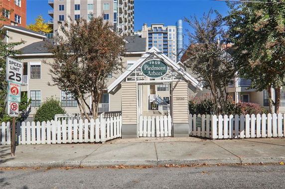 Front view of a two-story building with a white picket fence and a gated entrance.