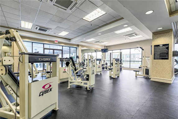 Indoor gym area featuring exercise machines and large windows.