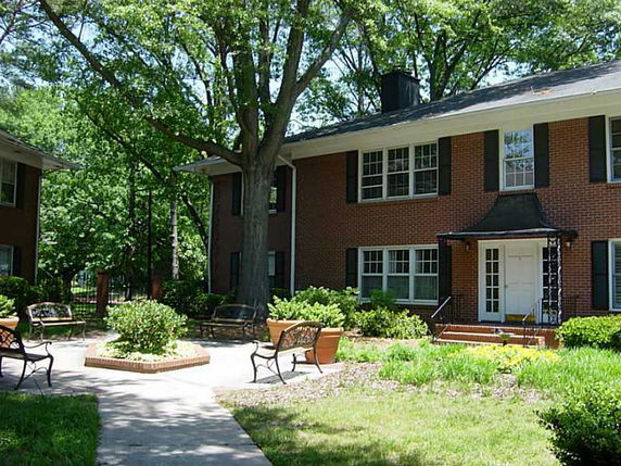 Front view of a two-story brick house with a black roof and white framed windows.