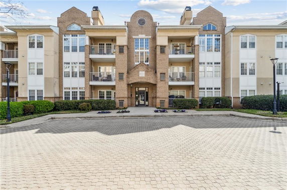 Front view of a multi-story apartment building with balconies and brick facade.