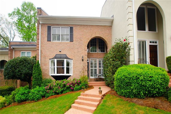 Front view of a two-story brick house with large windows and an arched entryway.