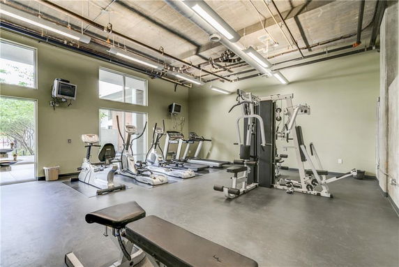 Interior view of a gym with exercise equipment and windows.