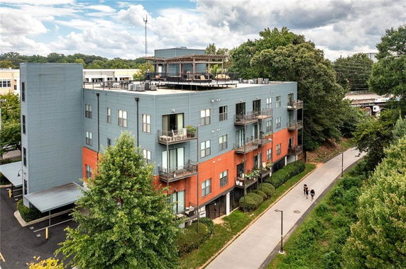 Front view of a multi-story apartment building with balconies and a rooftop terrace.