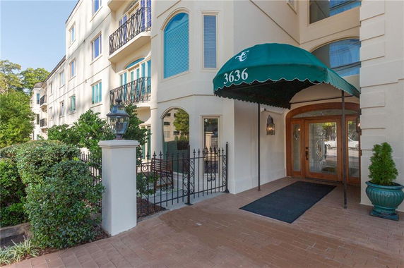 Front view of a multi-story building with a green awning and decorative iron balcony railings.