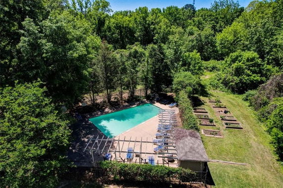 Aerial view of a swimming pool surrounded by trees and greenery.