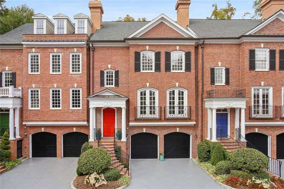 Front view of a brick townhouse with multiple stories and a double garage.