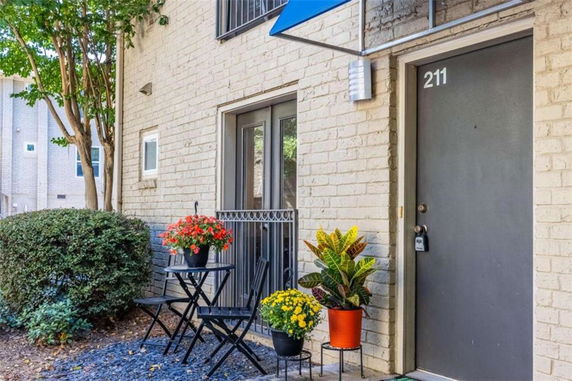 Front view of a building with a gray door marked 211 and a small outdoor seating area.