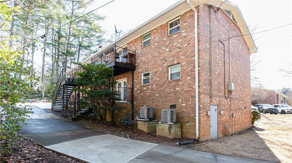 Side view of a two-story brick building with external staircase and balcony.