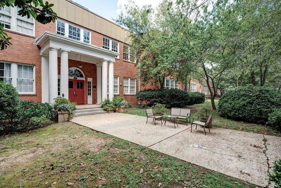Front view of a two-story brick building with white columns and red doors.
