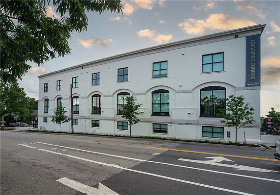 Front view of a three-story building with large windows and a sign indicating loft-style condos.