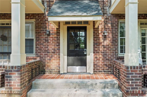 Front view of a brick house entrance with a black door and porch.