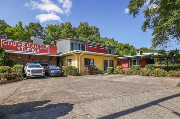 Front view of a studio building with a colorful facade and a parking area.