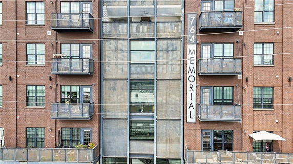Front view of an apartment building with balconies and a vertical sign reading '764 Memorial'.