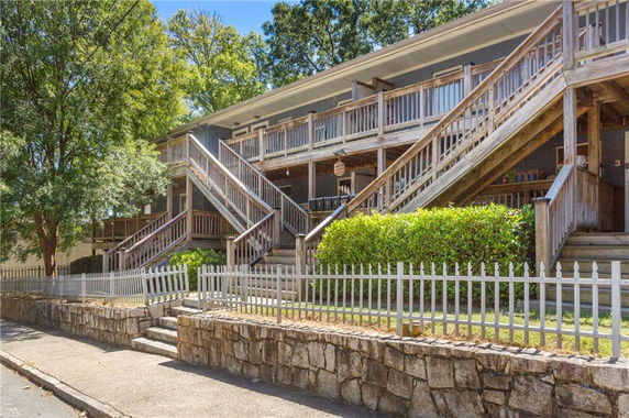 Front view of a multi-story building with wooden staircases and a porch.