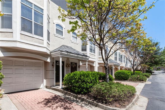 Front view of a multi-story townhouse with garages and decorative columns.