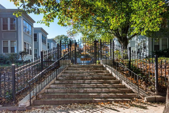 Front view of apartment buildings with a staircase and wrought iron fencing.