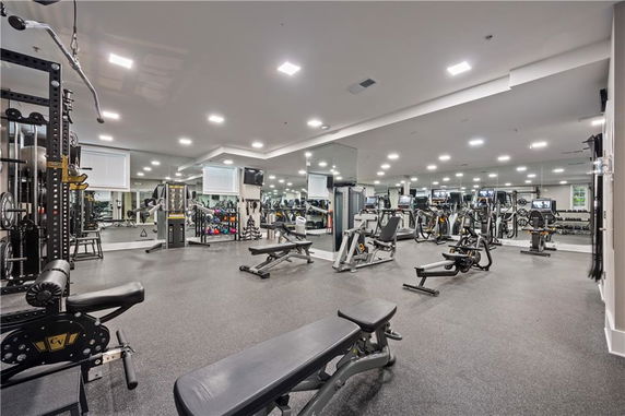 Indoor gym area with various exercise equipment and mirrors on the walls.