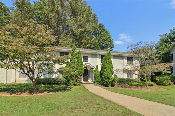 Front view of a two-story house with a central entrance and surrounding trees.