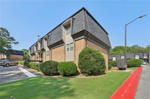 Angled view of a two-story building with a brick facade and dark shingled roof.