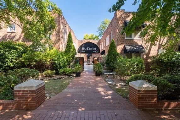 Front view of a brick building entrance with a pathway and greenery.