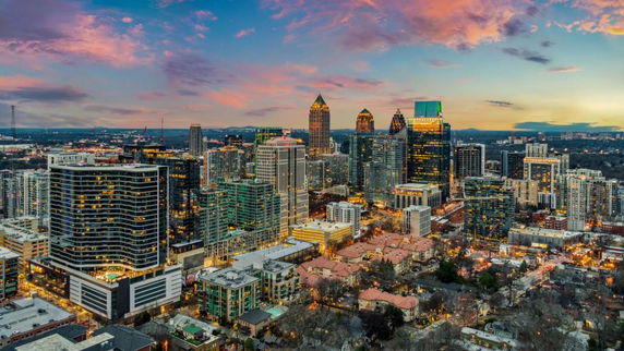 Panoramic view of a city skyline with tall buildings and skyscrapers at sunset.