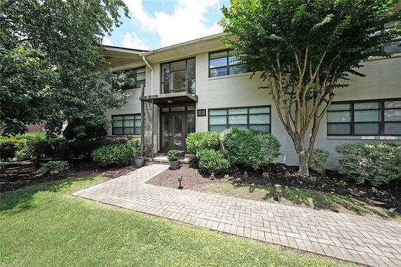 Front view of a two-story building with large windows and landscaped entrance.