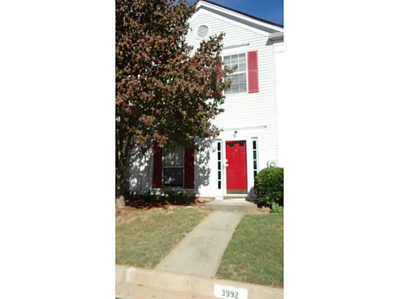Front view of a two-story house with red door and shutters.