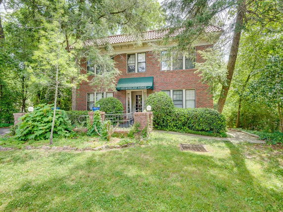 Front view of a two-story brick house with a green awning over the entrance.