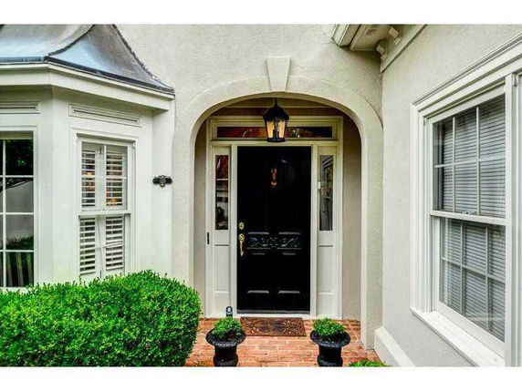 Front view of a house entrance with an arched doorway and a black door.