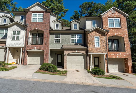 Front view of a multi-story townhouse with brick and siding exterior.