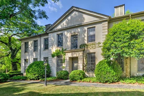 Front view of a two-story house with an elegant facade and lush greenery.