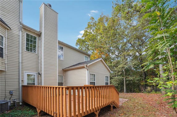 Rear view of a house with a chimney and a wooden deck.