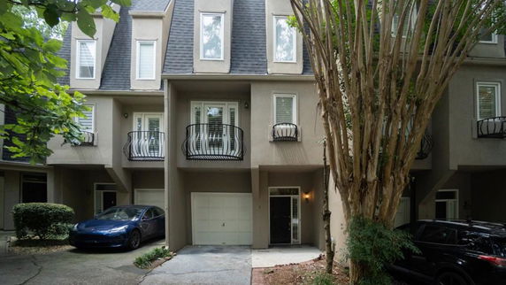 Front view of a multi-story townhouse with a garage and balconies.