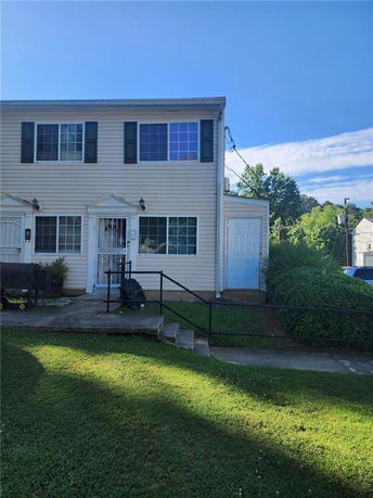 Front view of a two-story townhouse with multiple windows and a small entrance porch.
