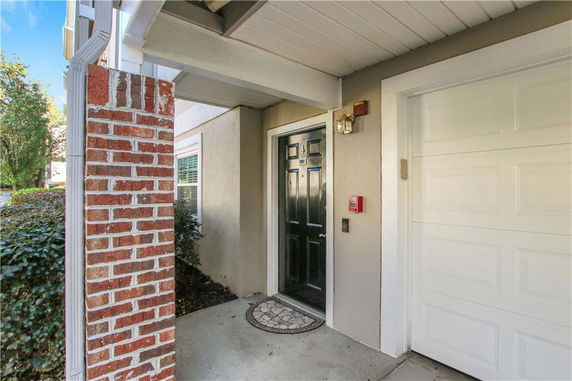 Front view of a house entrance with a brick column, black door, and attached garage.